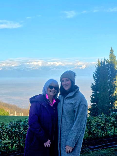       Two people posing in front of mountains.
  