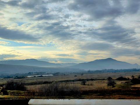 Wide landscape of distant mountains under cloudy sky.