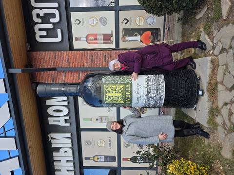 Two women posing with a large decorative bottle.