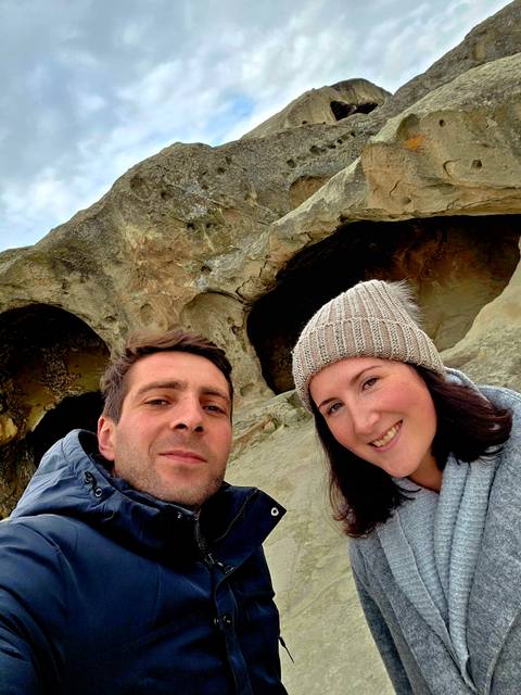       Two people smiling in front of rocky cliffs.
  