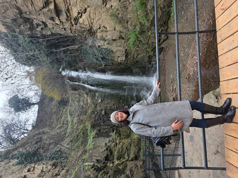Person posing next to a waterfall.