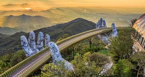       A scenic view of the Golden Bridge held by giant hands in the mountains at sunrise.
  