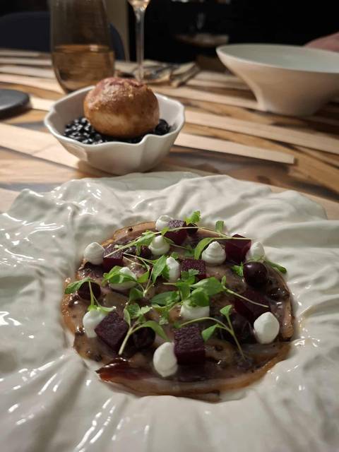      A plated dish with garnishes, surrounded by a white decorative plate.
  