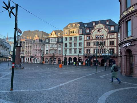 Mainz city square with historical buildings, trees, and a few pedestrians.