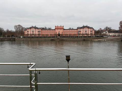 Stately building by the riverside with cloudy skies.