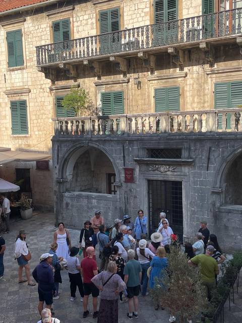 Tourists sitting at a stone open area with historic architecture.