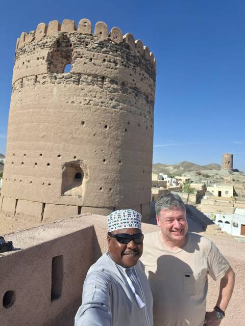 Couple posing near ancient towers with a mountainous backdrop.
