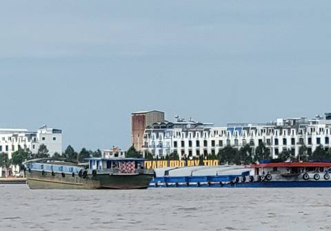 Cargo boats on a river with cityscape in the background.