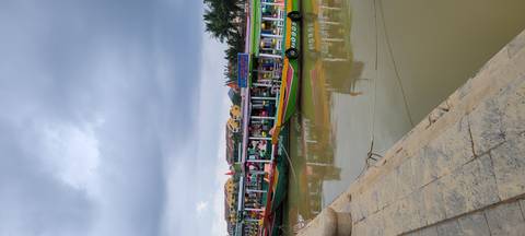 Boats lined up on a river under a cloudy sky.