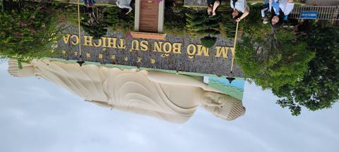 Reclining Buddha statue with people around.