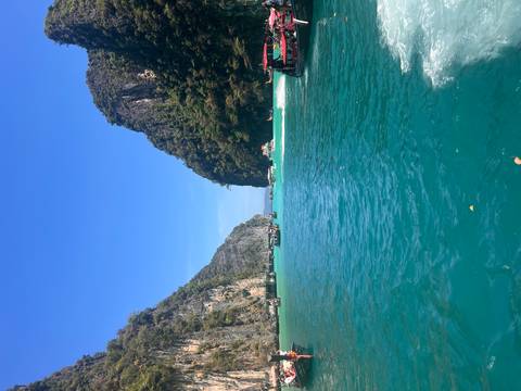 Boats in turquoise waters between steep cliffs.