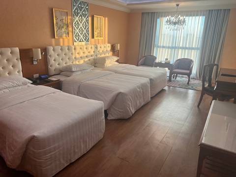 Hotel room with three beds and a window view.