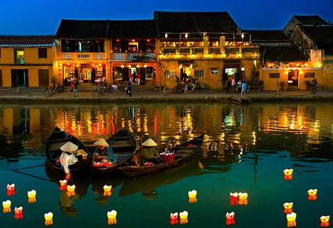Boat ride on a river in front of colorful buildings with lanterns.
