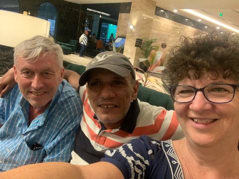       Three people posing together indoors.
  