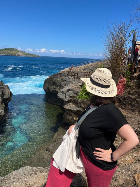 Woman overlooking a rocky coastline and vibrant blue sea.