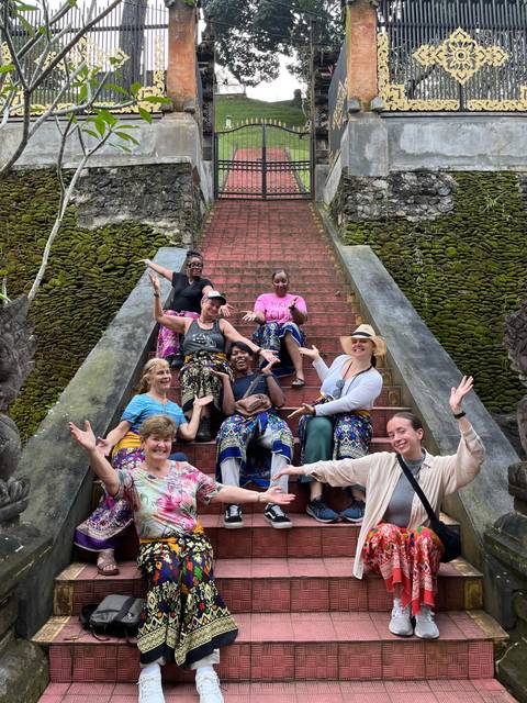 Group of tourists cheerfully posing on temple steps.