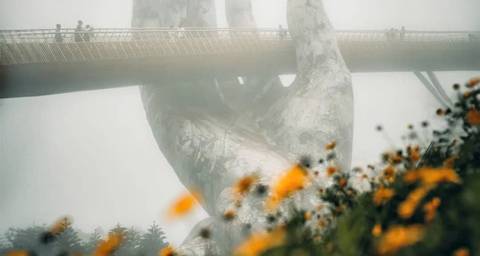 Golden Bridge in fog with wildflowers in the foreground.