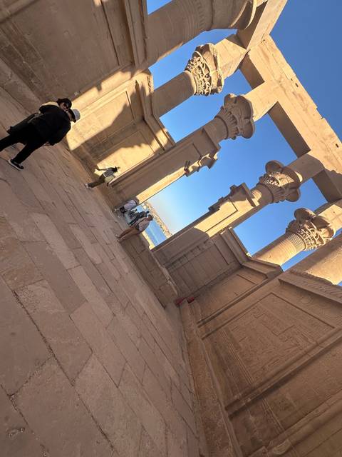       Tourists exploring an ancient temple with large pillars.
  