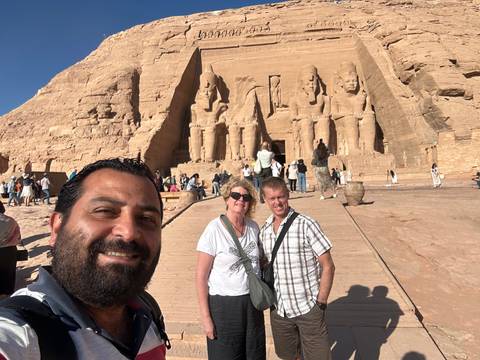 Group of tourists posing in front of ancient statues.