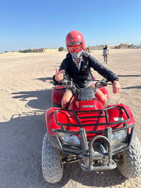 Person on an ATV in a desert landscape wearing safety gear.