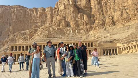       Tour group standing in front of large ancient rock temple.
  