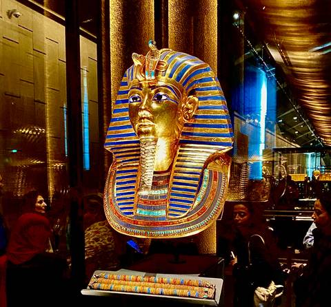 Gold mask artifact on display in a museum setting.