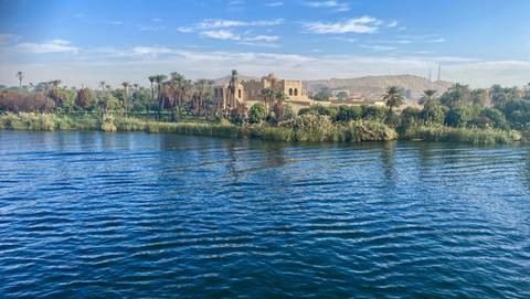 Lush landscape beside a large river with historical building.