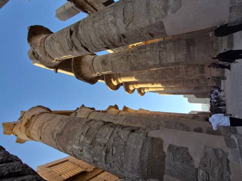 Egyptian temple with columns and tourists wandering around.