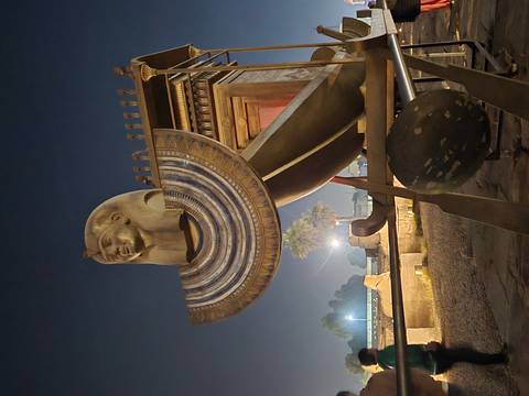 Ancient Egyptian statue and artifacts lit up at night.