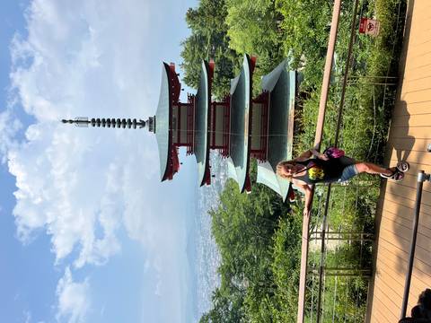 A woman posing in front of a traditional pagoda with scenic views.
