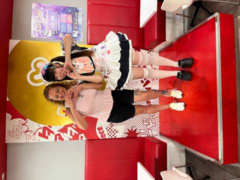       Two people posing inside a colorful themed cafe.
  