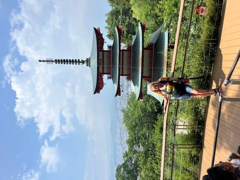       A woman posing in front of a traditional pagoda with scenic views.
  