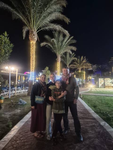 Family posing in a park at night with decorative lights.