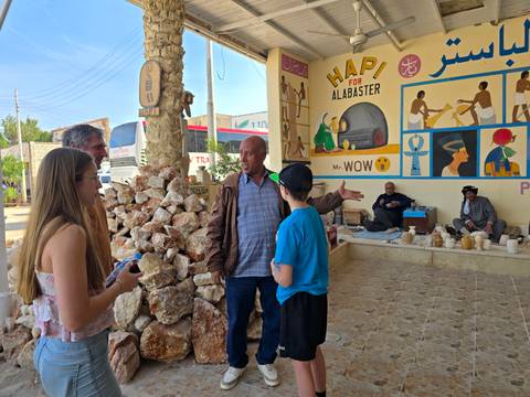       Family interacting with a local guide near shops.
  