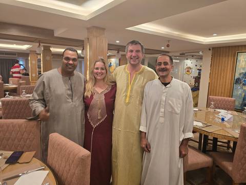 Group dressed in traditional clothing posing in a dining area.