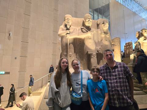       Family posing in front of large statues in a museum.
  