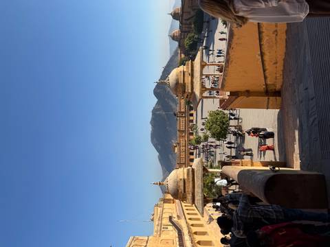       Amber Fort with people and mountains in the background
  