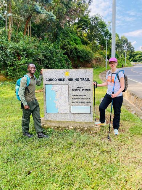 Hikers standing next to a Congo Nile Trail sign.