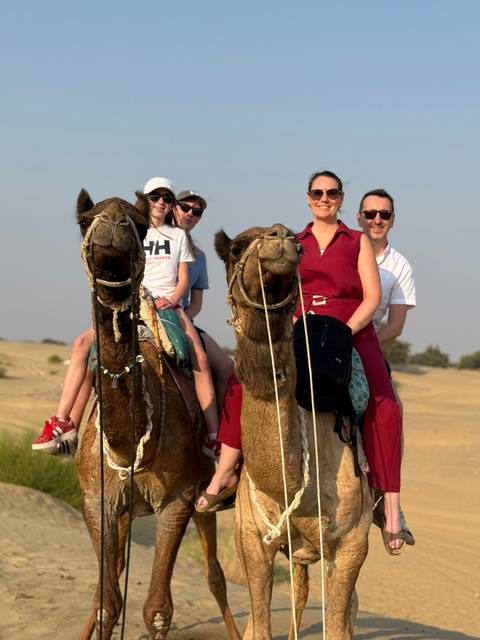 Two couples riding camels together in a desert setting.