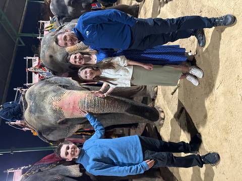 Family posing with an elephant at night under artificial lighting.