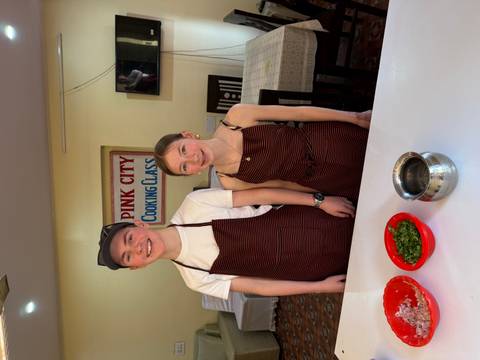 Two individuals in cooking class apparel preparing ingredients.