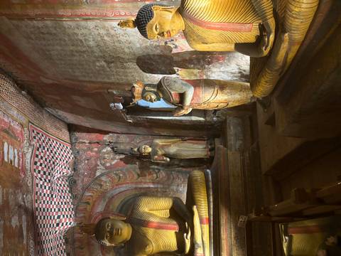 Interior view of a temple with ancient statues and intricate paintings.