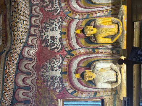 Decorative Buddhas inside a temple with colorful walls.