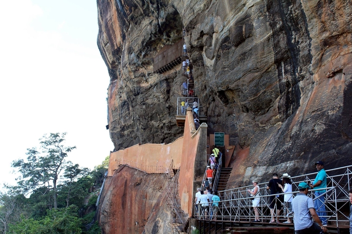 Crowd of tourists climbing a staircase along a cliff.
