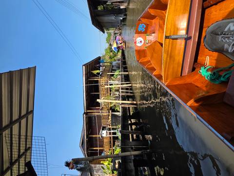 Wooden boat navigating through canals with traditional houses in background.