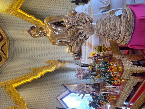 Golden statue of Buddha in a richly decorated temple in Bangkok.