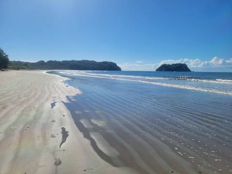 A tranquil beach with gentle waves and clear skies.