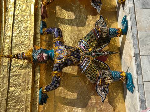       Colorful guardian statue in front of a golden temple wall.
  