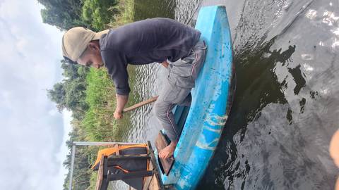 Person canoeing in calm water with vegetation around.