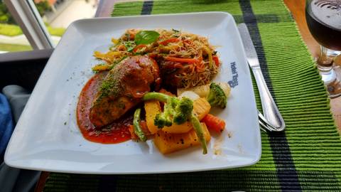 Gourmet dish with meat, sauce, and a variety of vegetables.